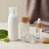 Unlabelled cleanser, toner, gel moisturiser and serum bottles arranged on cream linen for an oily skin routine